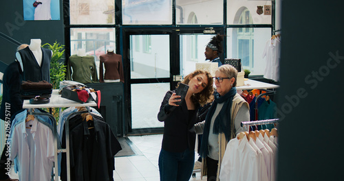 Foto Elderly client takes pictures with her niece in clothing store, having fun while they are doing a shopping spree at the mall