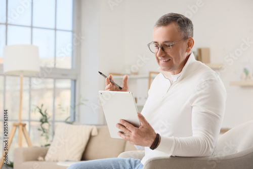 Smiling mature man using di...