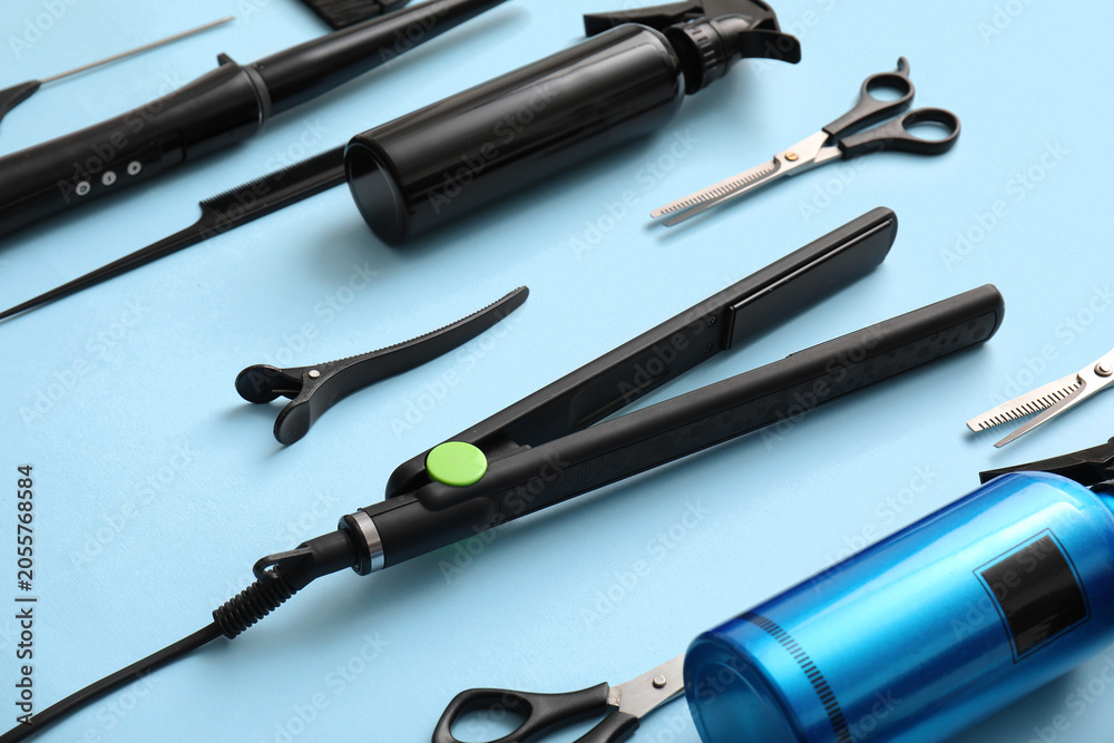 Fototapeta premium Professional hair styling tools and equipment for salon or home use flat iron scissors combs and spray bottles on blue background