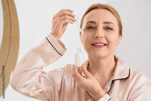 Mature woman applying anti-...