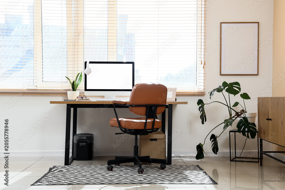 Fototapeta premium Modern home office workspace with blank computer screen, ergonomic chair, and indoor plants for remote work setup