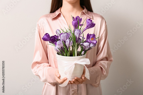 Fotografie Woman in pink silk blouse holding white potted purple crocus flowers with ribbon