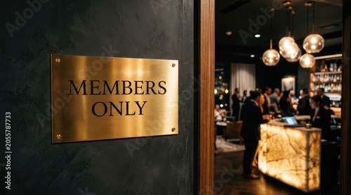 Elegant brushed brass sign with bold black text indicating members only access mounted on a dark textured wall interior surface