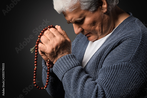 Elderly man praying with ro...
