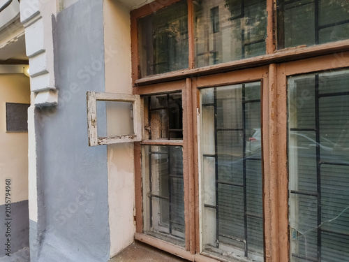 Facade of an old building with sun reflections in the windows glass. Small open leaf window, old rotten frames in the city street. Different angles