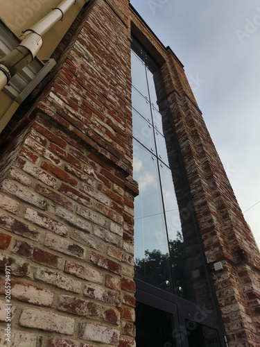 Old red brick building in the city center. Clean windows of a house with blue sky reflections in the clear glasses. Day sun light