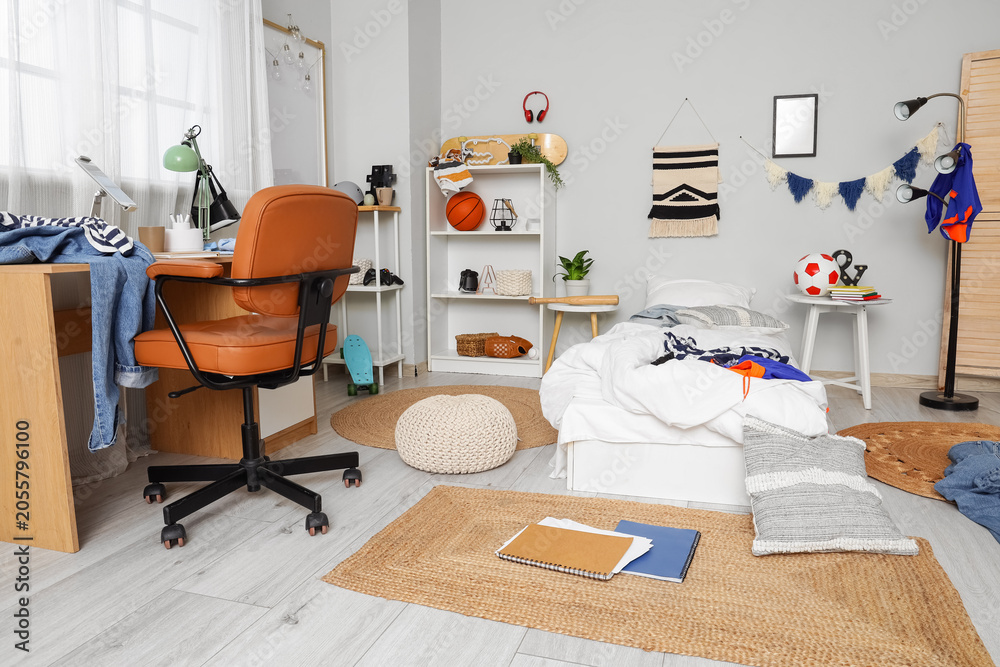 Fototapeta premium Interior of messy teenagers room with bed, workplace and shelf units