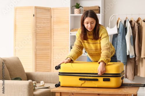 Young woman packing suitcas...