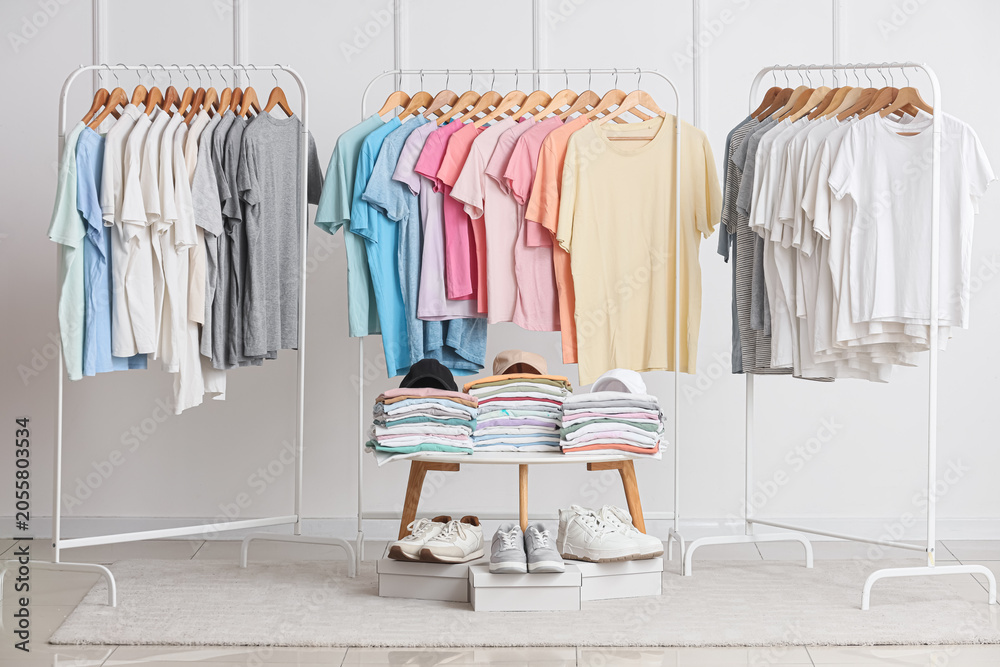 Fototapeta premium Retail clothing display with assorted t-shirts on racks, folded stacks, and sneakers for fashion merchandising