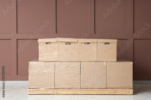 Bild auf Leinwand Cardboard moving boxes wrapped in plastic on wooden pallet for relocation and st