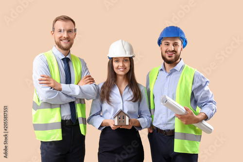 Group of engineers with house model on beige background