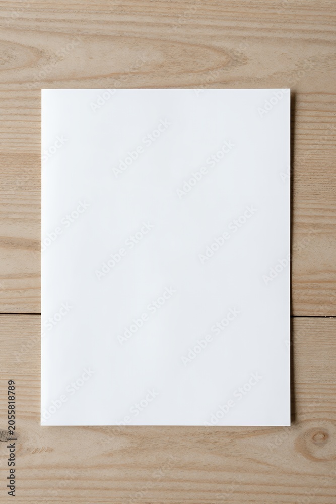 Naklejka premium Blank white paper on wooden table