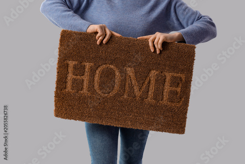 Young woman with doormat on...