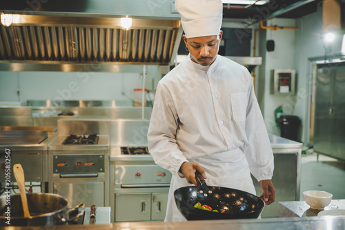 Culinary student practicing wok cooking with vegetables during professional kitchen training