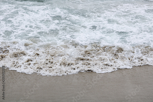 Ocean water bubbles washing over an empty coast, showing natural liquid movement and splash details.