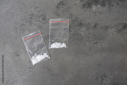 Foto Two small plastic ziplock bags containing white crystalline powder substance on a dark textured background