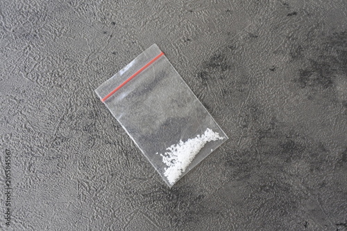 Картината върху платно Single plastic ziplock bag filled with white crystalline powder on a dark grey textured surface