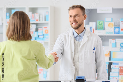 Foto Smiling pharmacist shaking hands with customer in pharmacy, professional healthc