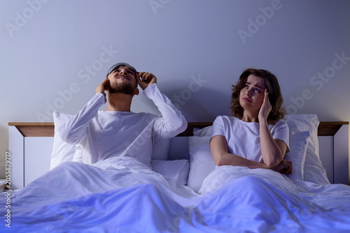 Fotografia Young couple suffering from noisy neighbours in bedroom at night