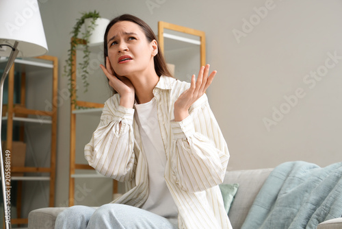 Fotografía Young woman suffering from noisy neighbours on sofa at home