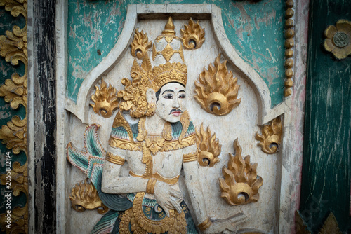 Balinese mythological deity carving, a vibrant cultural symbol creating a rich, spiritual backdrop with intricate gold leaf detail and painted wood texture in Indonesia