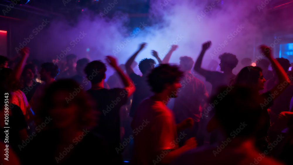Obraz premium Group of friends celebrating with hands raised in vibrant nightclub with colorful lighting