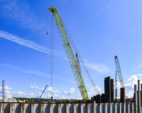 Port industrial cranes on the river and unloading warehouse on a clear sunny day