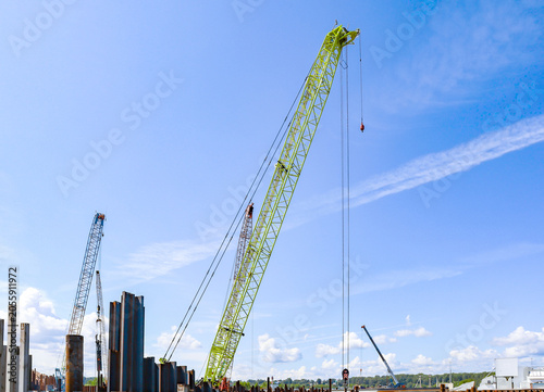Port industrial cranes on the river and unloading warehouse on a clear sunny day