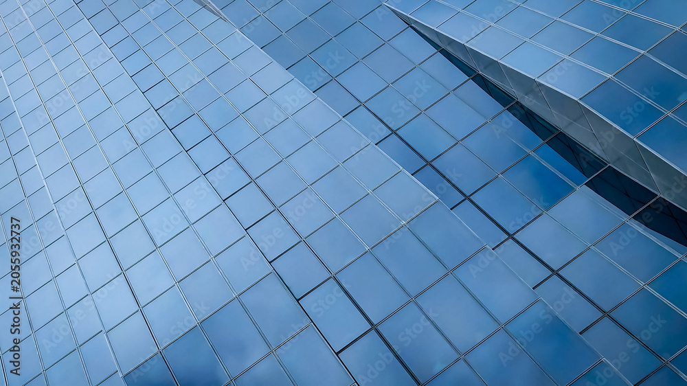 Fototapeta premium Modern glass facade of a tall skyscraper building with abstract geometric architectural details in Vienna Austria corporate business district