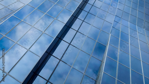 Modern glass facade of business office building skyscraper with blue sky and white clouds reflection in Vienna Austria