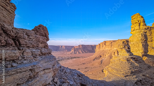Stunning desert canyon view with massive sandstone rock formations and cliffs in Saudi Arabia at sunset