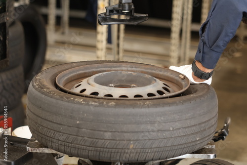 Close-up of the process on a tire-changing machine: a mechanic dismounts a car wheel (removing a tire from or mounting one onto a stamped steel rim).