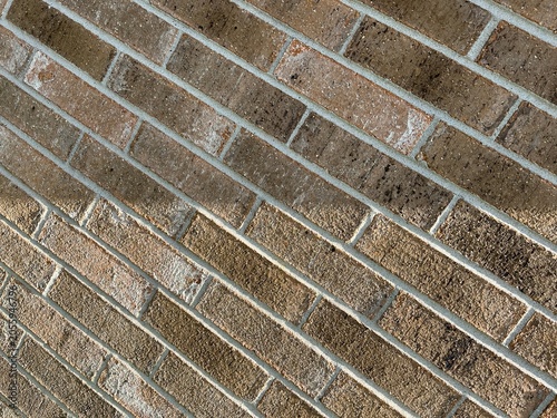 Diagonal Brown Brick Wall Texture with Natural Shadow. Shadow over a brownish brick wall background. Artistic brick wall with perspective and a line shadow.