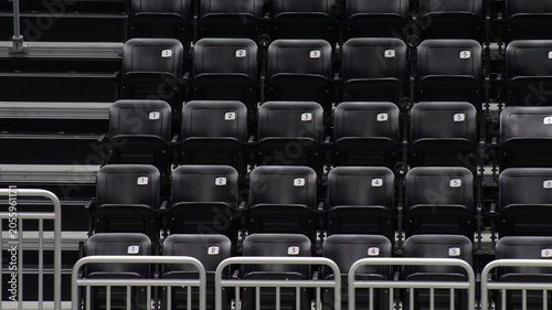 Canvas Print Black seats at an arena in a college campus with stairs on the left and a metal divider in front