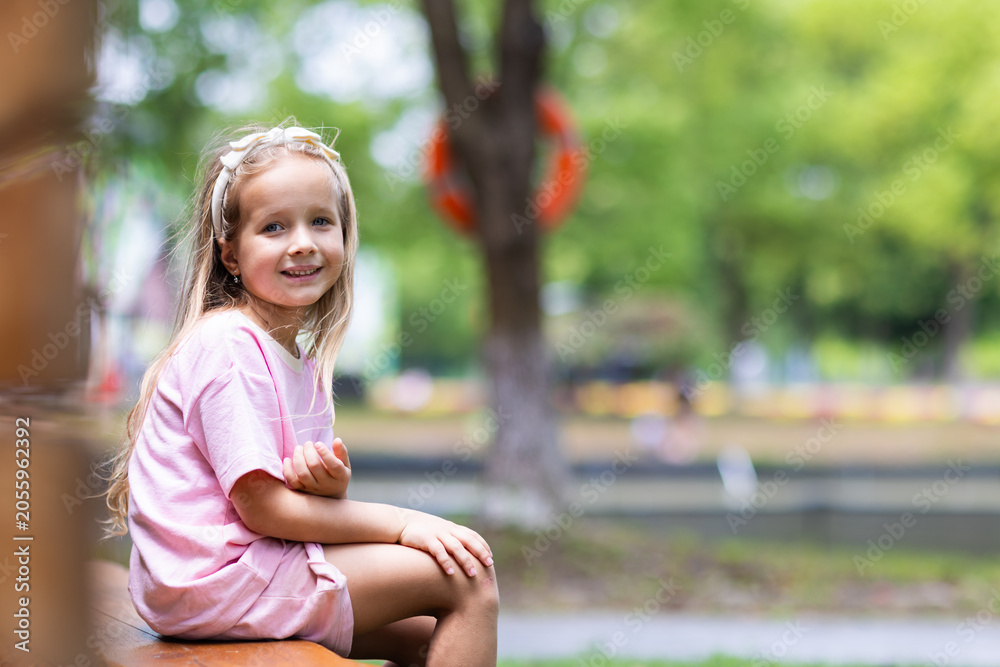 Naklejka premium Smiling Little Girl Sitting Outdoors in Park