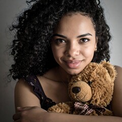 A young girl with curly hair and a teddy bear