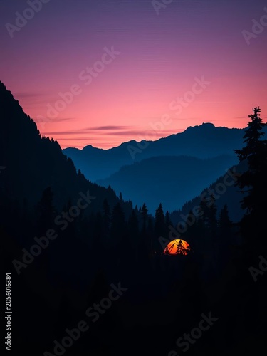Twilight forest landscape with glowing orange tent amidst dark mountains, outdoor, forest exploration