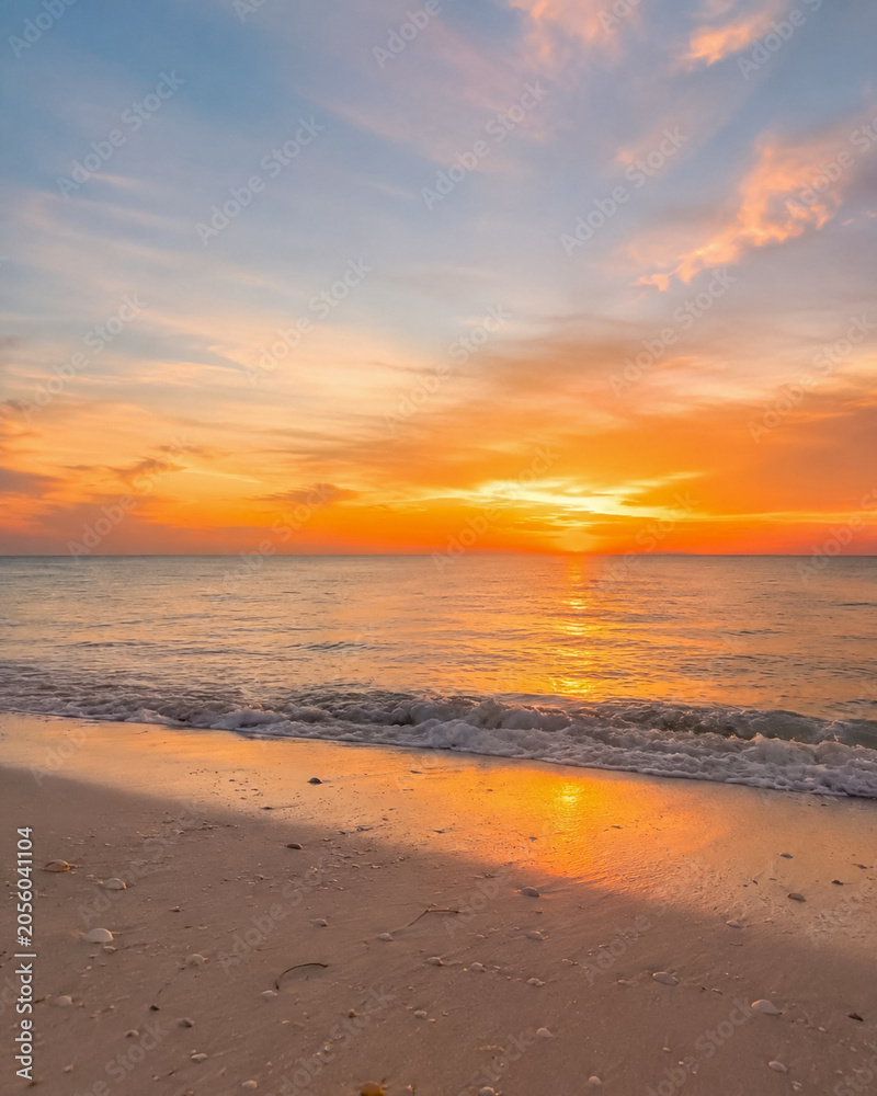 Fototapeta premium Golden Sunset Over Calm Tropical Beach with Gentle Ocean Waves
