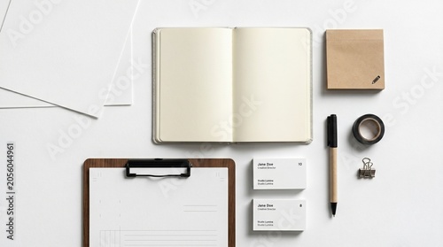 Office supplies arranged on white surface including notebook clipboard envelopes