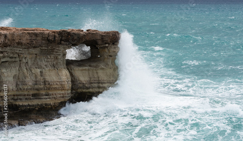 Ocean waves crashing against rocky sea cliff. Sea caves Cape Greko