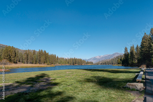 Hume Lake Green Lawn with Red Canoe and Snow-Capped Mountain View California