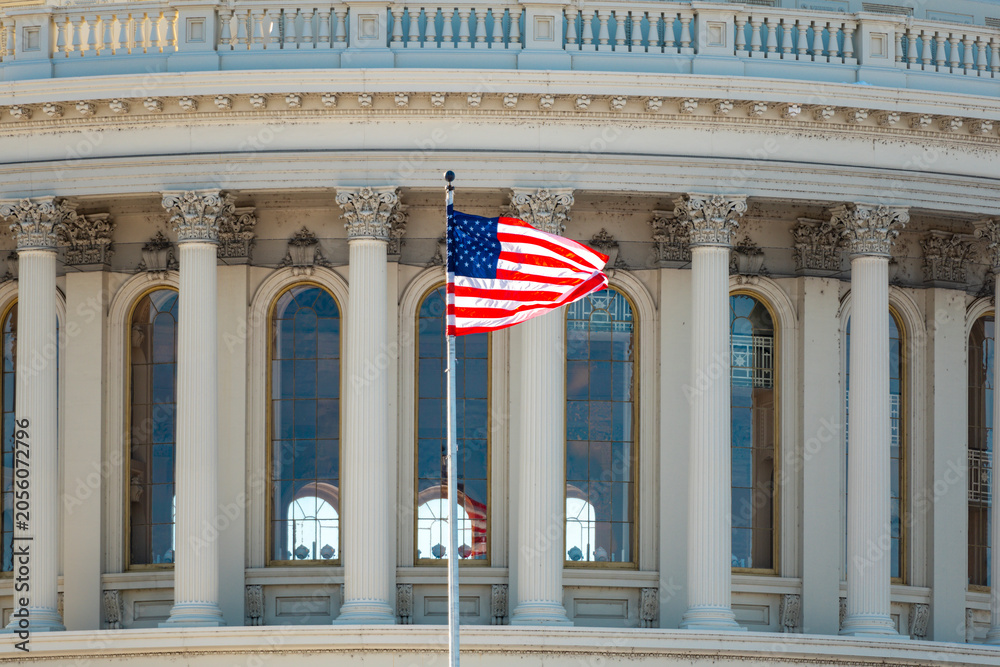 Naklejka premium Capitol with american flag near famous landmark. Us flag on capitol with columns. American flag near capitol as national symbol. Capitol with american flag.