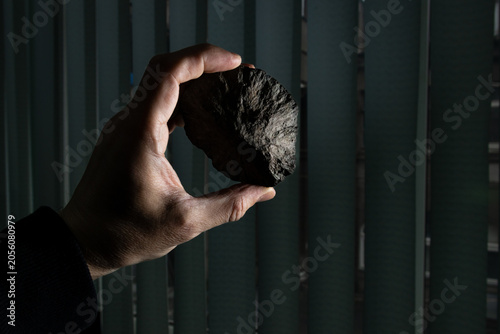 Fotografija Holding a natural phosphorite round-shaped rock stone in hand at a laboratory, b