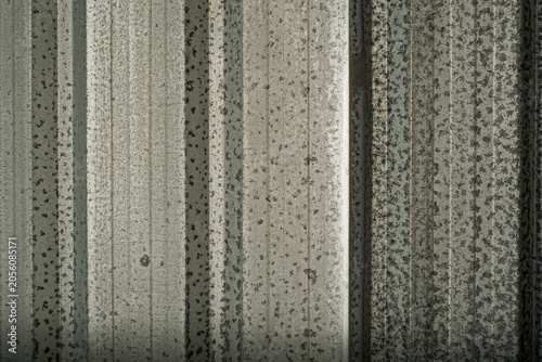Slika na platnu A detailed close-up shot of a weathered corrugated galvanized iron sheet showing heavily mottled spangle patterns, dark oxidation spots, and vertical ridges on a metallic industrial panel surface