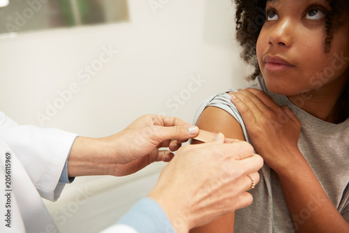 Doctor applying adhesive bandage on patient's arm in medical room