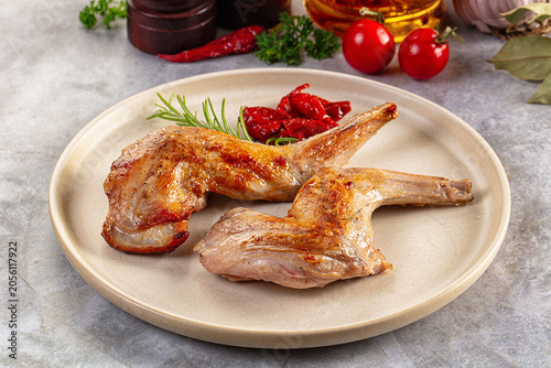 Photography Roasted rabbit legs served with rosemary and tomatoes