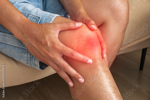 Fényképezés Man with inflamed knee pain sitting indoors, arthritis injury discomfort, orthopedic treatment and rehabilitation concept
