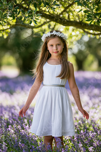 a young girl standing in a field of purple flowers.