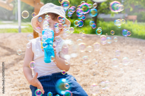 Blurred image for background of a little kid blowing soap bubbles on a playground in summer