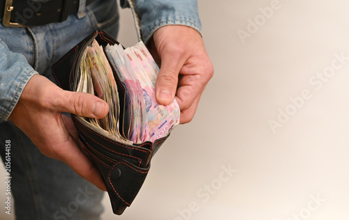 Fotografie Money stack taken from open wallet in hands of man
